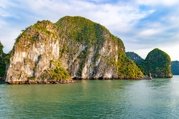 Limestone mounts covered with dense forest in Halong Bay, Vietnam. Halong Bay is famous for its emerald waters and thousands of limestone islands covered in tropical forests.