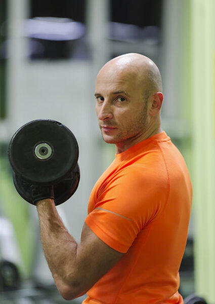 Sporting man is engaged in training in fitness center