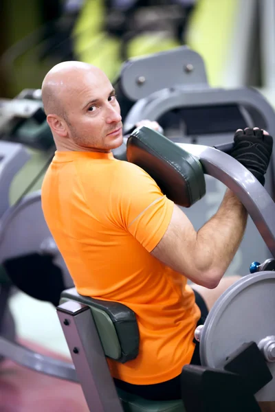 Sporting man is engaged in training in fitness center — Stock Photo, Image