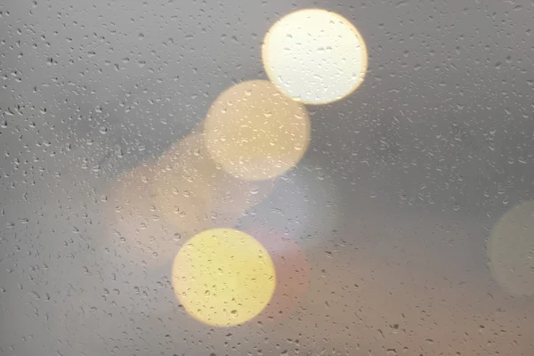 Drops of rain on glass with defocused lights — Stock Photo, Image