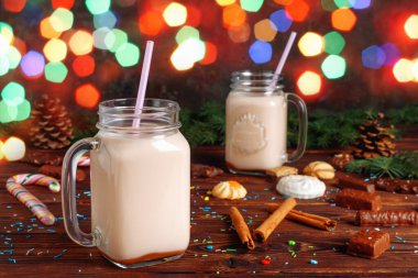 İki bardak sıcak kakao, sütlü, tarçınlı, şekerli ve saman tüplü Noel köknarı ve bulanık bokeh kozalaklı.