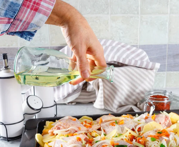 Adam zeytinyağı döküyor çiğ tavuk sebze ve baharatla