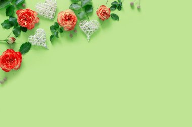 Hasır kalpli güzel kırmızı güller yeşil kağıt arka planda.