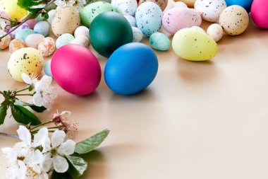 Renkli yumurtalar ve kağıt bej arka planda kiraz dallarıyla güzel bir Paskalya kartı. Metnin için kopyalanmış çiçek tebrik kartı.