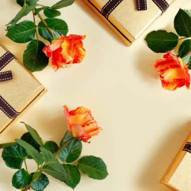 Altın hediye kutulu güzel pembe güller ve narin sarı kağıttan arka planda yay. Düğün için tebrik kartı.