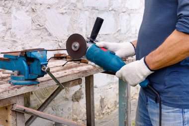 İşçi, evin arka bahçesinde elektrikli aletler, çekiç ve kerpetenle tamirat yapıyor..