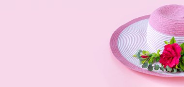 Güneşli bir günde gül buketi ve okaliptüslü güzel bir hasır şapka. Doğanın pembe kağıt arka planı.