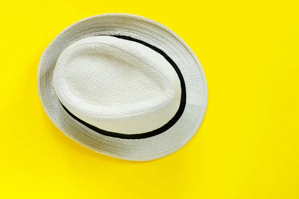 Fashionable straw white hat on yellow paper background