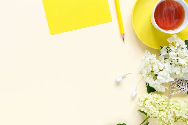 带笔记本 热茶和黄色背景的水壶的家庭写字台顶部视图 — 图库照片