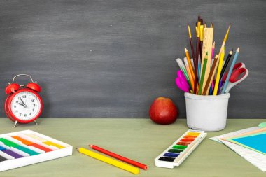 Mesaj için yer olan okula geri dön. Web tasarımı için yatay pankart. Okul malzemelerinin parlak bir şekilde toplanması. Çalışma için masaüstünde kalemler, boyalar, plastikler, çalar saat ve elma var..