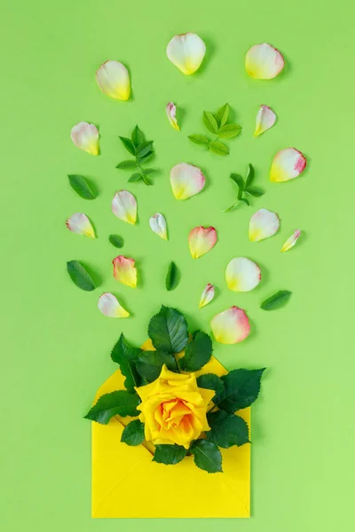 緑の背景に封筒に黄色のバラの花束 春休みのミニマルなコンセプト — ストック写真