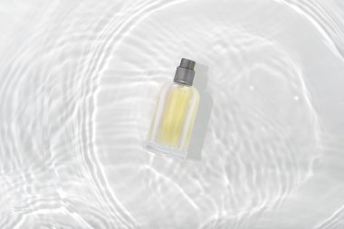 Kozmetik parfüm şişesi beyaz arka planda daireler çizerek su yüzeyine sıçrıyor. Cam püskürtme tüpü tanıtım pankartı tasarımı.
