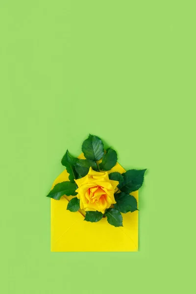 緑の背景に封筒に黄色のバラの花束 春休みのミニマルなコンセプト — ストック写真