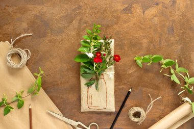 Paket kağıdına sarılı bir buket kırmızı gül ve boyalı vazo. Antika ambalaj kağıtları, dekorasyon için hanımeli dalları..