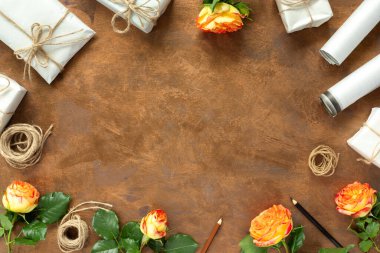 Kağıt ambalajlı hediyeler, klasik sarı paket kağıtları, rulo, ip ve süsleme için kalemler. Altın sarısı arka planda sarı güller.