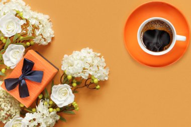 Beyaz ortanca ve turuncu arka planda gül çiçekleri olan hediye kutusu. Bir fincan sıcak kahve. Tatil için kavramsal kartpostal.