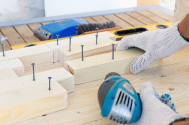 Dolap ustası, matkap, çivi ve çekiçle ahşap mobilyalar yapıyor. Ev yapımı atölyede.