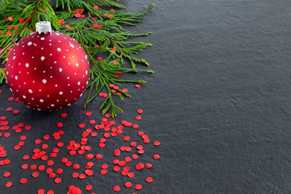 赤いクリスマスのおもちゃのボール 休日のコンフェッティと黒の背景にクリスマスツリーの枝 — ストック写真