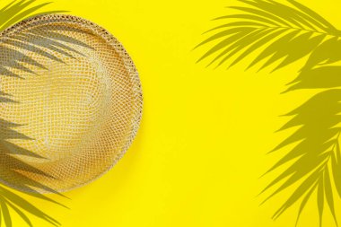 Sarı kâğıt üzerinde palmiye yaprakları olan şık hasır şapka.