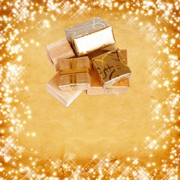 Gift box in gold wrapping paper on vintage cardboard background — Stock Photo, Image