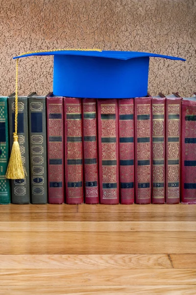 Examen mortarboard ovanpå högen med böcker på abstrakt rygg — Stockfoto