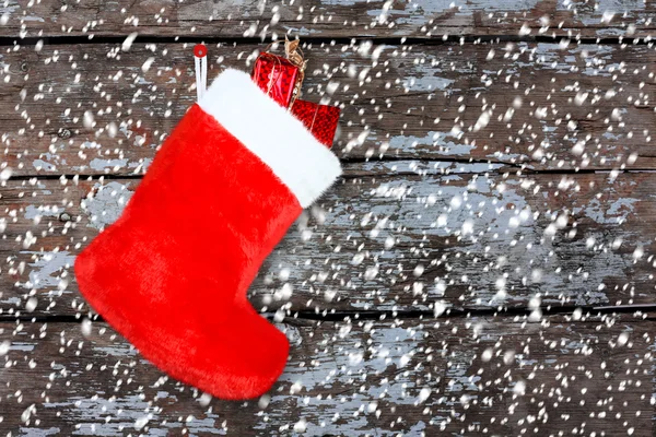 Bota de Natal vermelho com presentes na parede de madeira de fundo — Fotografia de Stock