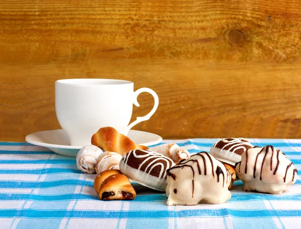 Чашка чая и вкусное печенье на голубой клетчатой скатерти — стоковое фото