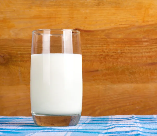 Glass of fresh cow's milk on blue tablecloth — Stock Photo, Image