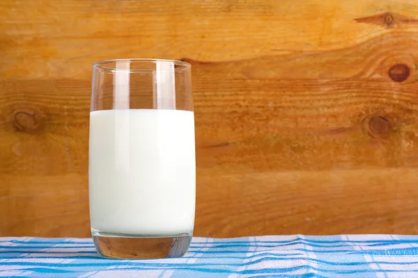 Glass of fresh cow's milk on blue tablecloth — Stock Photo, Image