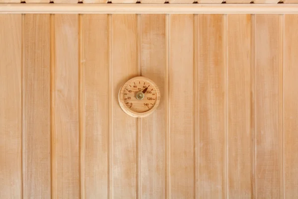 Круглый термометр на стене традиционной деревянной сауны — стоковое фото