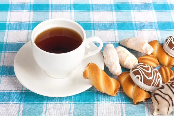 Cup of tea and delicious cookies on blue checkered tablecloth — Stock Photo, Image