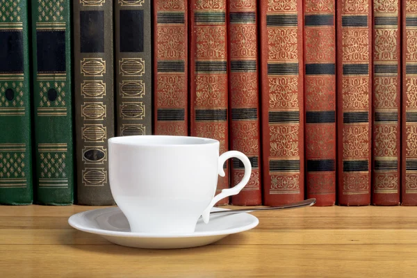 Taza caliente de café fresco en la mesa de madera y una pila de libros — Foto de Stock