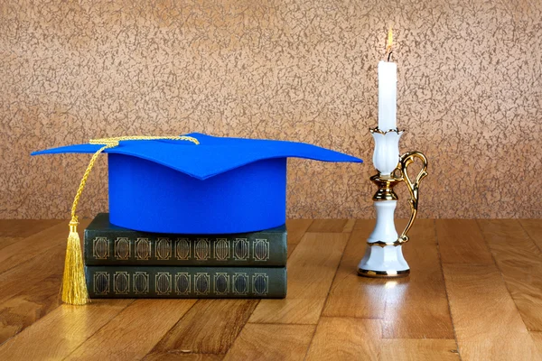 Graduation mortarboard on top of stack of books on abstract back — Stock Photo, Image
