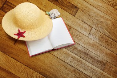 Eski püskü ahşap arka plan üzerinde kitap ve kırmızı deniz yıldızı ile hasır şapka