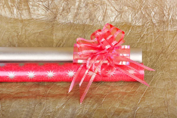 Rolls of multicolored wrapping paper with red bow for gifts on g — Stock Photo, Image