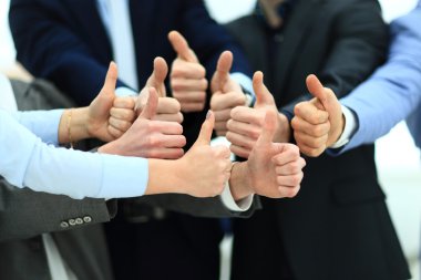 Close-up of business team holding their thumbs up clipart