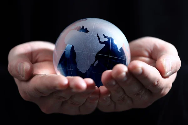Mão segurando globo translúcido com fundo azul — Fotografia de Stock
