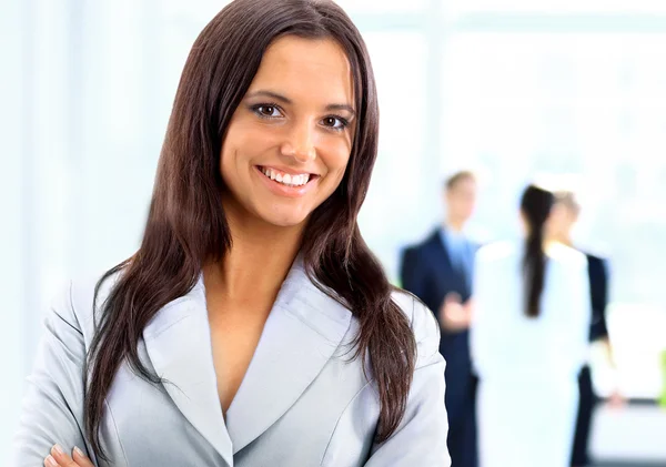 Donna d'affari in piedi con il suo personale in background in ufficio — Foto Stock