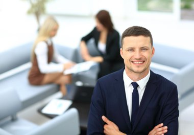 Gülümseyen iş adamı ile onun Meslektaşlarımız arka planda duran bir