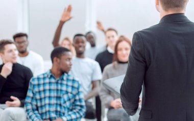 Konuşmacı ve çeşitli genç dinleyiciler bir konferans odasında