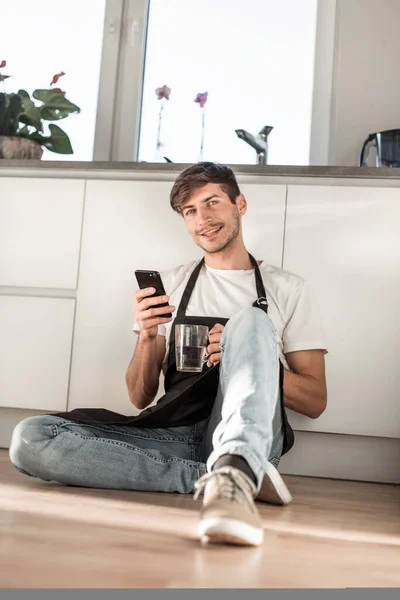 Jeune homme avec verre d'eau lecture SMS sur son téléphone — Photo
