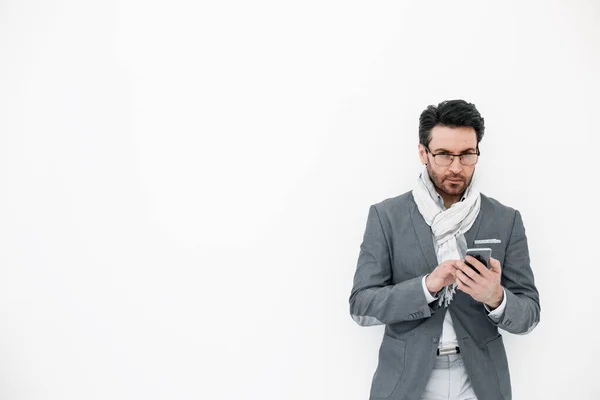 Biznesmen z szalikiem na szyi wpisując SMS na smartfonie. — Zdjęcie stockowe