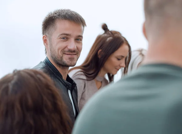 Aantrekkelijke jongeman zitten in de cirkel van zijn vrienden — Stockfoto