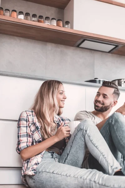 年轻夫妇坐在厨房地板上喝咖啡 — 图库照片
