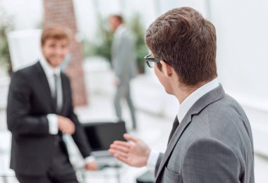 Yan görünüş. Ofiste duran dost canlısı iş adamı..