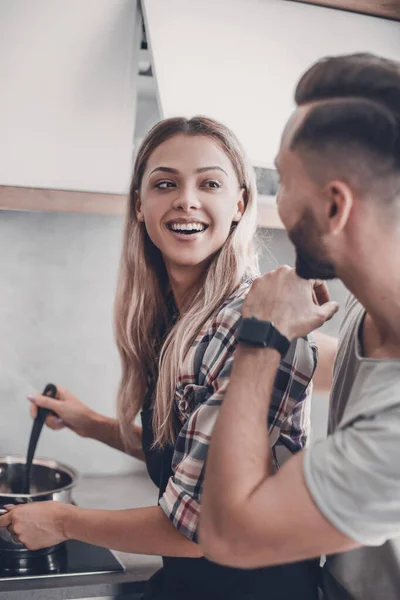 Młody człowiek żartuje ze swoją żoną w kuchni — Zdjęcie stockowe