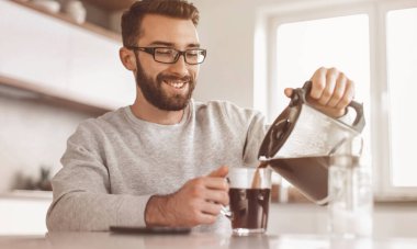 Çekici adam kendine bir fincan sabah kahvesi dolduruyor.