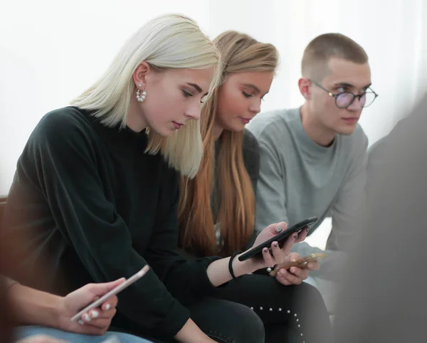 De près. femme avec smartphone assis parmi ses amis — Photo