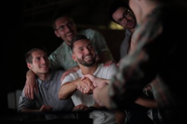 Ofis masasında el sıkışmaktan mutlu çalışanlar.