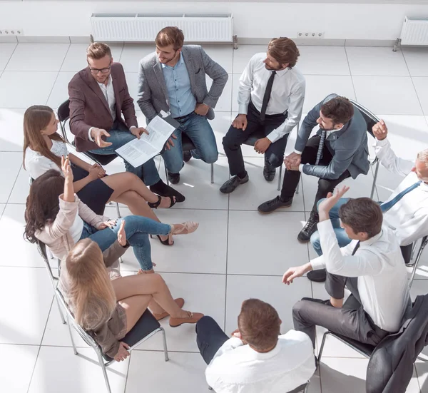 Equipo de jóvenes empleados sentados en un círculo en la sala de conferencias . — Foto de Stock